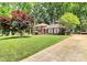 Beautiful brick home showcasing a lush front yard, mature trees, and an inviting driveway at 1024 Regency Dr, Charlotte, NC 28211