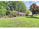 Charming brick home with white shutters, surrounded by mature trees and a spacious front lawn at 1024 Regency Dr, Charlotte, NC 28211