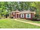 Quaint brick home with white shutters, set amidst a lush green lawn and mature landscaping at 1024 Regency Dr, Charlotte, NC 28211