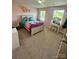 Bright bedroom with pink walls, carpeted floors, a bed with colorful bedding, and a vanity near the window at 1070 Glenbriar Ct, Woodleaf, NC 27054