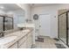 Well-lit bathroom with double vanity, granite countertop, framed mirrors, and a glass-enclosed shower at 11062 Discovery Nw Dr, Concord, NC 28027