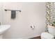 Cozy half bathroom with pedestal sink, unique floral wallpaper, and dark wood floors at 11062 Discovery Nw Dr, Concord, NC 28027