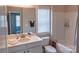 Well-lit bathroom featuring a combined bathtub and shower with a white vanity and commode at 1424 South St, Cornelius, NC 28031