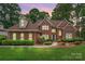 Well maintained brick two-story home featuring manicured lawn and mature trees against a dusky sky at 15535 Eagleview Dr, Charlotte, NC 28278