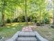 Lush backyard landscape with a charming brick path leading to a serene water feature and mature trees at 166 Wilson Lake Rd, Mooresville, NC 28117