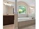 Elegant bathroom with a soaking tub, vanity with granite countertop, and natural light from an arched window at 166 Wilson Lake Rd, Mooresville, NC 28117