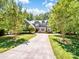 A stately home with a long driveway, lush trees, and manicured lawn provides great curb appeal at 166 Wilson Lake Rd, Mooresville, NC 28117