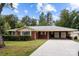Charming red brick home with attached carport, lush landscaping, set against a blue sky at 3430 Stokes Ferry Rd, Salisbury, NC 28146