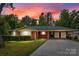 Charming red brick home with attached carport, lush landscaping, and a beautiful sunset backdrop at 3430 Stokes Ferry Rd, Salisbury, NC 28146