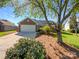 Charming brick home featuring a two-car garage and a beautifully landscaped front yard with mature trees on a sunny day at 4656 Chaucer Nw Pl, Concord, NC 28027