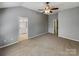 Spacious carpeted bedroom with neutral paint, ceiling fan, and entry to the main bathroom at 4656 Chaucer Nw Pl, Concord, NC 28027