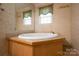 Bathroom featuring a large soaking tub with wood paneling and bright natural light at 5039 Pine Springs Dr, Bessemer City, NC 28016