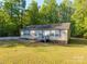 Single-story home featuring a quaint front porch surrounded by mature trees at 5039 Pine Springs Dr, Bessemer City, NC 28016