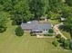 Aerial view of home featuring lush landscaping, a welcoming front porch, and detached garage in a verdant, wooded setting at 5159 Taxahaw Rd, Lancaster, SC 29720
