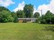 A cozy, single-story home boasts a well-kept lawn with mature trees at 5159 Taxahaw Rd, Lancaster, SC 29720