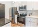 Modern kitchen featuring stainless steel appliances and sleek white cabinetry with hardwood floors at 5227 Pinebrook Dr, Charlotte, NC 28208