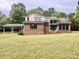 Spacious back exterior view of brick home with a carport and lush green lawn and mature trees at 611 Stowe Rd, Clover, SC 29710