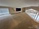 View of a carpeted bonus room with a window with blinds, overhead lighting and a railing looking over the main floor at 102 Eagle Ln, New London, NC 28127