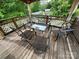A cozy outdoor deck featuring a glass-topped table surrounded by metal chairs and shaded by an umbrella at 102 Eagle Ln, New London, NC 28127