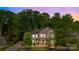 A stunning twilight view of a two-story home surrounded by lush green trees under a vibrant purple sky at 11304 Preservation Ln, Charlotte, NC 28278