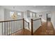 Upper hallway featuring a wooden railing, hardwood floors, and natural light from multiple windows at 11304 Preservation Ln, Charlotte, NC 28278