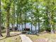 Wooded backyard leading to the lake with a fire pit and chairs at 1278 Island Creek Dr, Troy, NC 27371