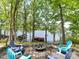 Wooded backyard leading to the lake with a fire pit and chairs at 1278 Island Creek Dr, Troy, NC 27371