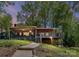 Charming lake house featuring a screened porch and deck overlooking a lush, wooded lot at dusk at 1278 Island Creek Dr, Troy, NC 27371