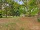 Spacious backyard with large shade trees and a storage shed at 1438 Larkfield Ln, Charlotte, NC 28210