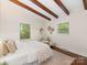 Bedroom featuring decorative wood beams, hardwood floors, and two bright windows at 1438 Larkfield Ln, Charlotte, NC 28210