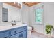Bathroom featuring blue cabinetry, a white toilet, and a window offering natural light at 1522 Stafford Ext, Monroe, NC 28110
