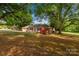 Single-story house with a red azalea bush, surrounded by large trees offering shade on a well-maintained lawn at 2007 Green Peach Rd, Lancaster, SC 29720