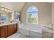 Primary bathroom showcasing a garden tub, large window and cherry wood cabinets at 204 Limerick Dr, Matthews, NC 28104
