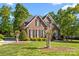 Beautiful two-story brick home featuring black shutters, arched windows, manicured landscaping, and lush green lawn at 204 Limerick Dr, Matthews, NC 28104