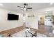 Open living room with a fan, hardwood floors, large-screen TV, and access to the kitchen and bedroom at 232 Avery St, Fort Mill, SC 29715