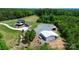 Aerial view features a home with metal roof, driveway, outbuildings, and wooded surroundings at 25674 Old School Rd, Oakboro, NC 28129