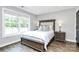 Bright bedroom with wood-look floors, large window, upholstered headboard, and side tables at 25674 Old School Rd, Oakboro, NC 28129