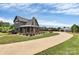 Exterior of a home with well-manicured grounds, a long drive, and an outdoor entertainment structure at 25674 Old School Rd, Oakboro, NC 28129
