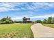 Stunning exterior of a well-manicured home with a long driveway, lush lawn, and vibrant landscaping with a covered car port at 25674 Old School Rd, Oakboro, NC 28129