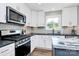 Well-lit kitchen with stainless steel appliances, white cabinets, and subway tile backsplash at 25674 Old School Rd, Oakboro, NC 28129