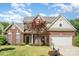 Inviting brick home featuring a well-kept front lawn, garden beds, and attached two-car garage at 3007 Sandbox Cir, Indian Trail, NC 28079