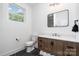 Bathroom features dark tile floor, wood cabinets, toilet and view of the shower at 302 Wesley Heights Way, Charlotte, NC 28208