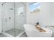 Modern bathroom featuring a freestanding tub, a glass-enclosed shower, and white marble-style tiling at 302 Wesley Heights Way, Charlotte, NC 28208