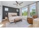 Primary bedroom with large windows, dark accent wall, a woven bench, and a comfortable leather chair at 302 Wesley Heights Way, Charlotte, NC 28208