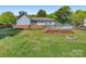 Grassy backyard featuring a deck, fire pit, and mature trees, perfect for outdoor enjoyment and entertaining at 308 Southland Rd, Huntersville, NC 28078