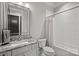 Well-lit bathroom featuring a marble countertop, white cabinets, a large mirror, and a tiled shower at 327 Kenway Loop, Mooresville, NC 28117