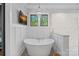 Elegant bathroom featuring a freestanding tub, decorative chandelier, and large format tile walls at 327 Kenway Loop, Mooresville, NC 28117