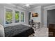 Bedroom featuring large windows, outdoor view, desk and chair, ceiling fan, and a large bed with dark quilt at 327 Kenway Loop, Mooresville, NC 28117