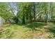 Scenic backyard featuring mature trees, a well-manicured lawn, and a charming white house in the background at 56 Blume Sw Ave, Concord, NC 28025