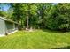 A beautifully maintained backyard features an outdoor seating area, a lush lawn, and mature trees at 5916 Rexwood Pl, Charlotte, NC 28210